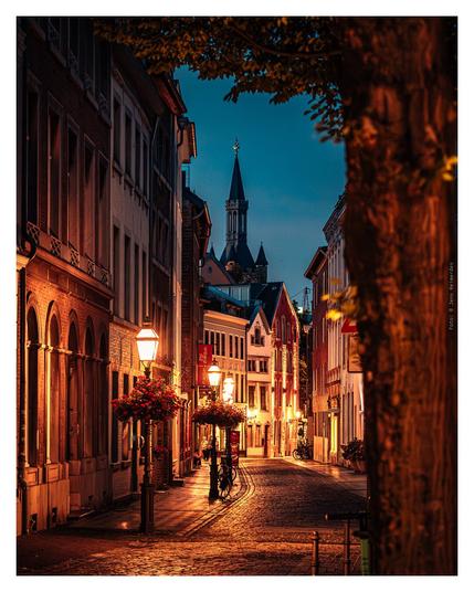 Photography of a serene night scene on Annastraße, Aachen, illuminated by warm glowing lights and a tower visible in the background.