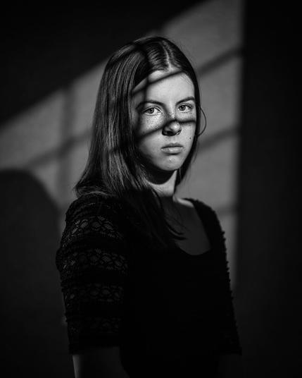 Studio portrait of a 12-year-old girl onto whom a window light with a window cross was projected by flash.