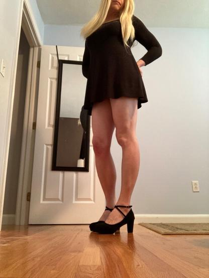 blonde woman with thigh length black dress and black strap high heels.