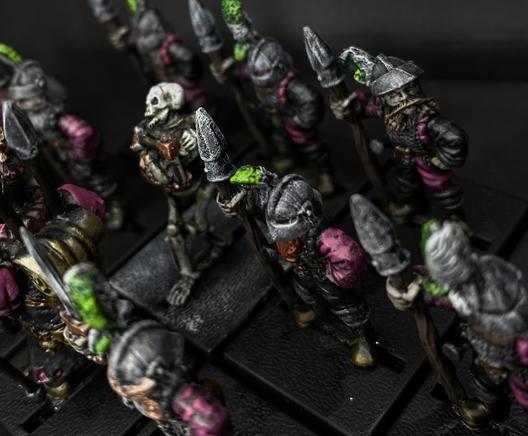 Over the head view of the regiment. The green and white feathers pop out , in the middle is the semi caged skeleton. Its torso and arms are bound in a lockbox.