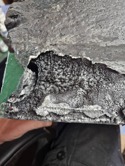 A close-up of the side of a black XPS foam cliff. This is the "outside" of the diorama, where it is smooth and will be left unpainted. Where the resin has heated up, it has melted a large, bubbly section of foam back.