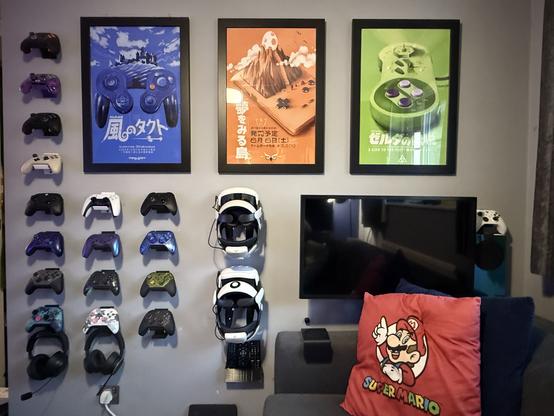 16 wall mounted controllers of various kinds and colors. 

We have:

Vader 3 Pro
Apex 4
Vader 4 Pro
King King 3 Max
Wolverine V3 Pro
Xbox Series X, purple/blue
Design Lab Elite Series 2, grey/orange
Design lab Xbox Series X, blue camo
PS5, white
PS5, purple/blue
Xbox 20th Anniversary, translucent black/green
Design lab Xbox Series X, white camo
ZD O+, blue
ZD O+, black
Elite Series 2, Halo edition
And finally, another Vader 4 Pro