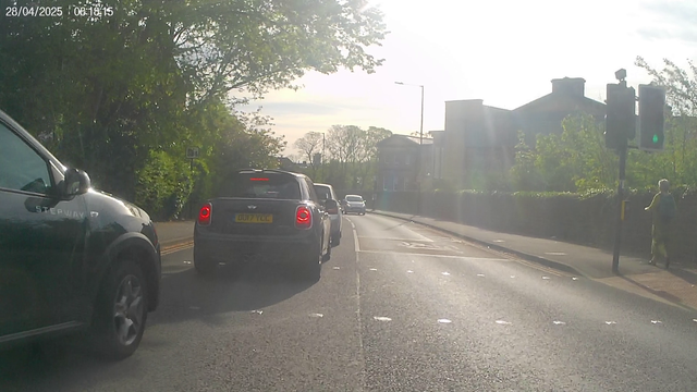 A cyclist view of a two lane road with stationary traffic in the near lane.