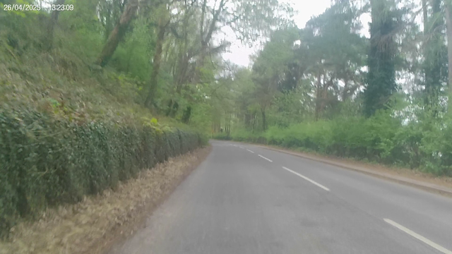 A cyclist view of a 2 lane road passing through woodland