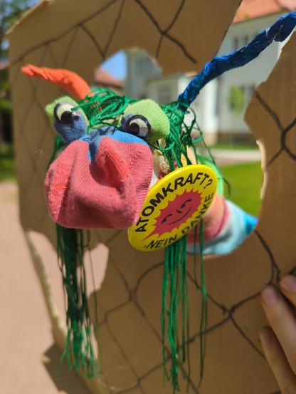 Buter Wurm mit Antenen, Augen, antiatom Sticker , der Wurm guck durch in Zaunloch aus Pappe
