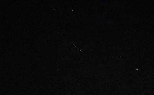 A chain of bright objects appears against the night sky.