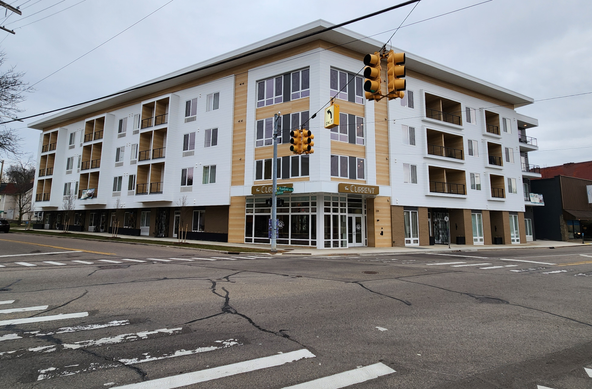 Photo of The Current, a new apartment building in the Creston neighborhood of Grand Rapids, MI (USA). The street intersection in front of the building is empty, all parking spaces are empty.