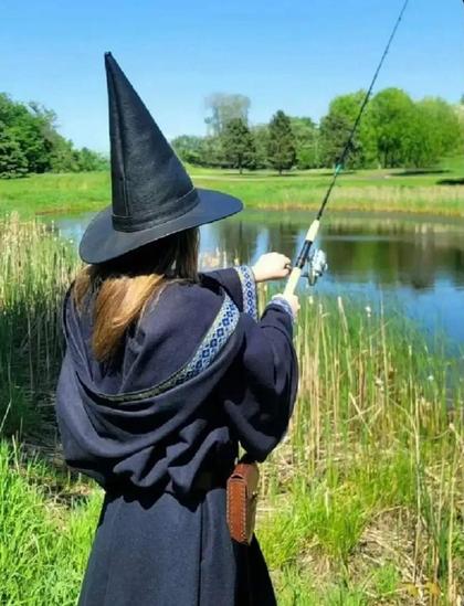 Une personne habillée en mage est en train de pêcher dans un étang
