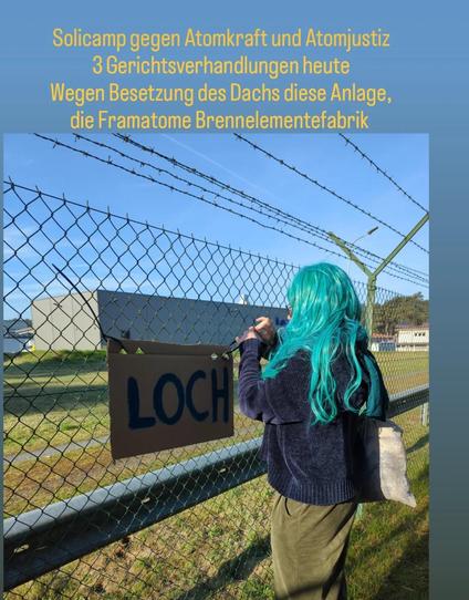 Mensch vrom Zaun der Brennelementefabrik     Gebäude im Hintergrund.  Am yzaun, Pappkarton mit dem Wort " Loch"