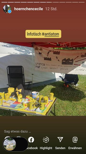 Infotisch mit Infomaterial, im Hintergrund Banner das den Weg vom Uran erläutert