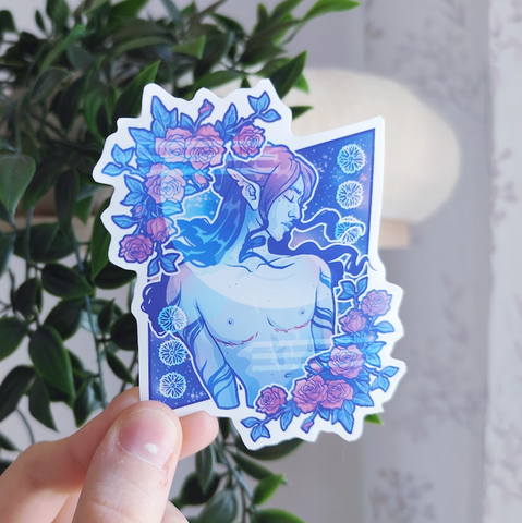 hand holding up a sticker of a trans man surrounded by roses