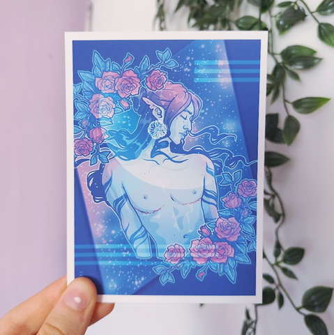 hand holding up an art print of a trans man surrounded by roses