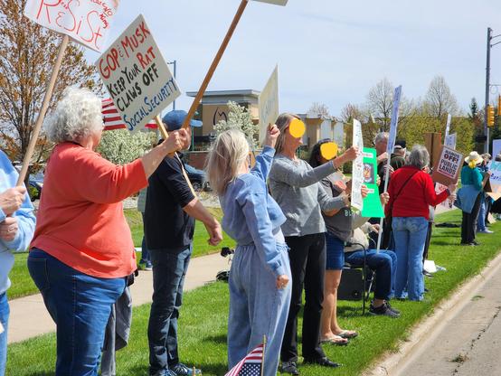 Several folks protesting holding signs, on green grass