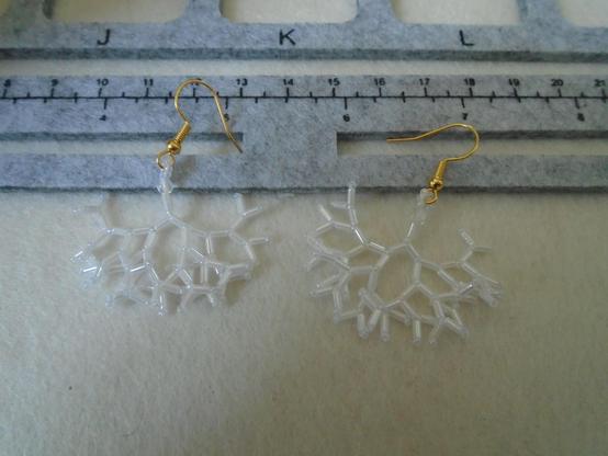 A pair of delicate white earrings, made mostly from bugle beads; they are alternated with tiny seed beads, and there is a larger crystal bead just under the base of the earwire.  From the top: gold earwire; small hanging loop made from seven of the tiny seed beads; crystal bead; bugle bead; seed bead; and then there are two bugle beads, each finished with a seed bead, coming out of that, then again two coming out of each of those, and so on, till you get six levels down altogether.  The result looks something like a cross between a snowflake and a rather sparkly tree root.