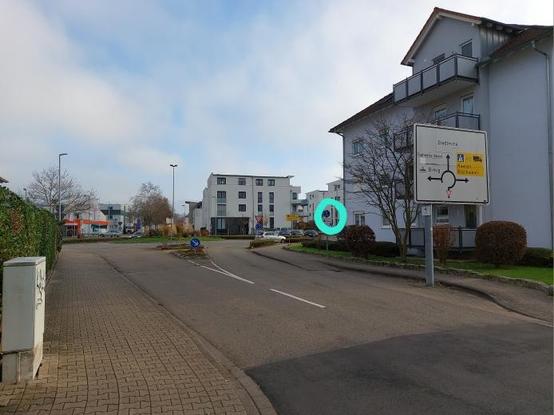 Blick vom linken Fahrbahnrand der Markgraf-Wilhelm-Straße in Richtung des Kreisverkehrs. Am rechten Rand ist die Rampe hoch zum Radweg im Seitenraum und das Verkehrszeichen 240 zu sehen.