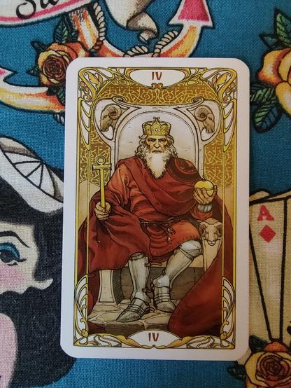 Card from the Golden Art Nouveau Tarot deck. 
The Emperor-IV. 
The emperor, an old man of white hair and beard, dressed in red robes with armor underneath sits on a throne. On his right hand a scepter. On the left hand a globe.