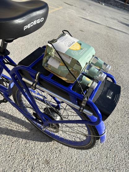 photograph of a 4pack of tonic water fitting perfectly on the carrier rack of an ebike