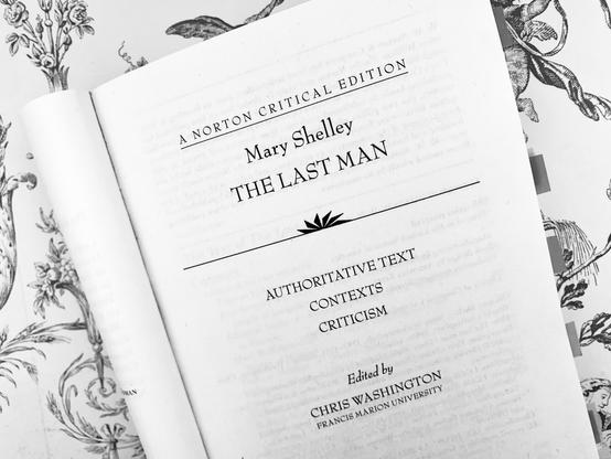 Pictured is the title page of the Norton Critical Edition of Mary Shelley's The Last Man. This black-and-white photo shows the book open against a backdrop of vintage wallpaper.