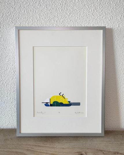 Stylized print of a dead bird, framed. It shows a blue tit, lying on its back. Yellow belly, all kinds of blueish greens for the wings and tail. The head is white with black collar and eye-line and a bright blue cap. Framed in a brushed aluminum frame, standing on a rough wooden plank, leaning against a white textured wall.
