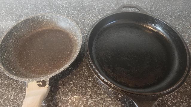 Cast iron pan next to a new pan that's coating is already brown handle is chipped