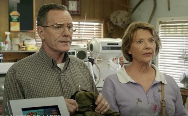 Bryan Cranston and Annette Bening stand at the counter of a small store ready to buy lottery tickets. They are both looking at the store clerk.