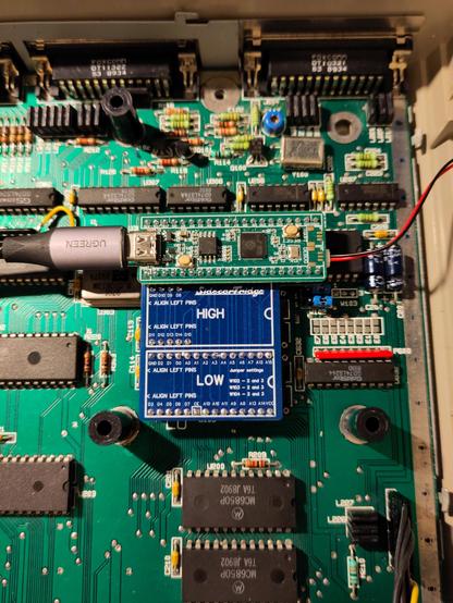 The Sidecartridge TOS Emulator hardware, as sits on the Atari STE mainboard. It plugs into the two ROM sockets, and there's a Pico-based ROM emulator PCB hanging out on the side.