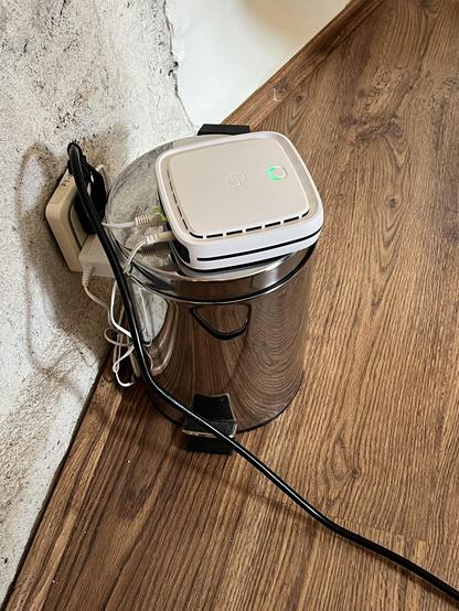 Ein WLAN-Router liegt auf einem kleinen Mülleimer in einer Ecke