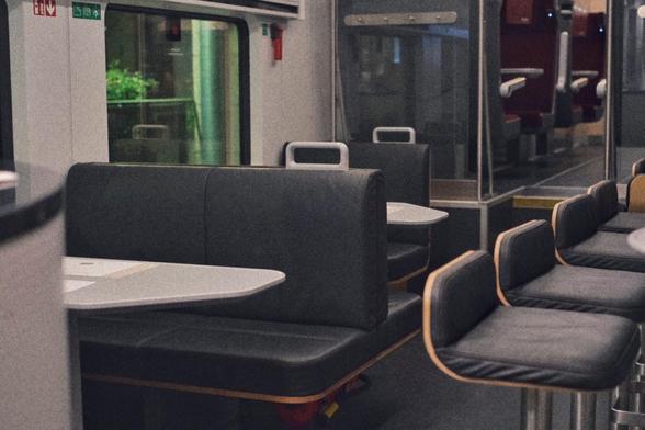 Dining car pictured from another position with its grey benches and bar stools.