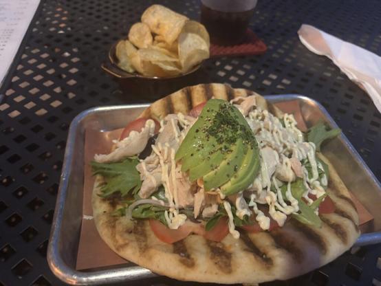 Grilled chicken with lettuce, tomato , avocado, dukes mayo , onion on a grilled pita with chips