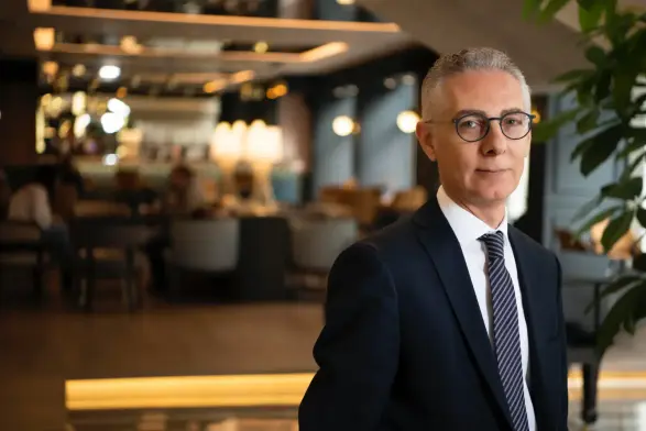 Barceló Hotel Group executive Hasan Ekmen in formal attire standing in a modern hotel interior