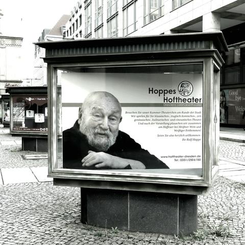 Schwarzweiß Foto

Sieben Stück stehen versetzt auf einem Fußweg.

Der vordere hier sichtbar.
Auf einem kleinen Podest befindet sich der gläserne Schaukasten, oben geschlossen mit flachen Dach, ca 15cm hoch.

Im Schaukasten Werbung für Hoppes Hoftheater.
Rolf Hoppe links im Bild.
Daneben ein Text für den Besuch des Theaters.