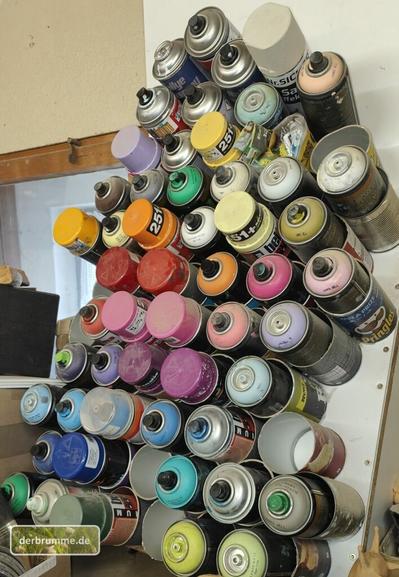 Ein paar Dutzend bunte Spraydosen in einem selbstgebauten Regal