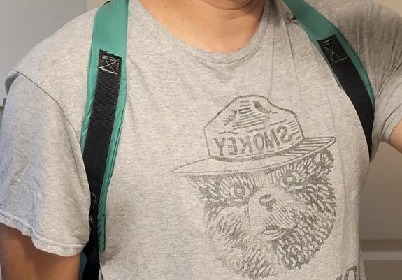 Backpack on shoulders of someone with a Smokey Bear shirt