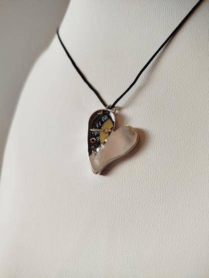 a heart shaped silver pendant with wristwatch elements and black cord
