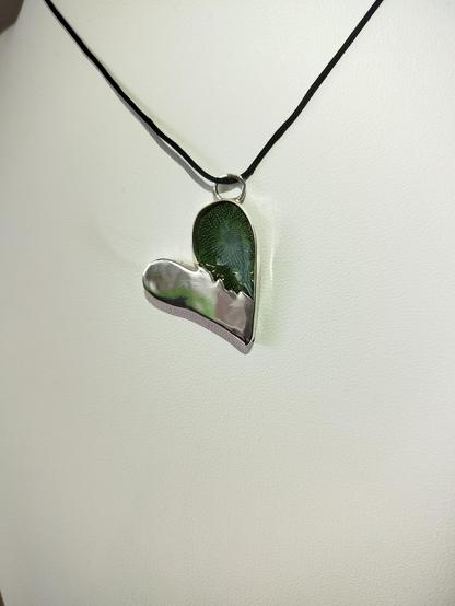 a heart shaped silver pendant with a pcb visible and black cord