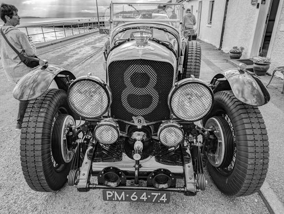 An old Bentley sports car, likely from the 1920's or 1930's registered in Holland with a number 8 painted on the big radiator grille.