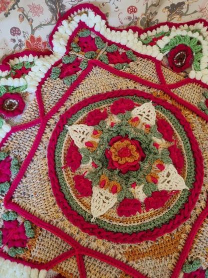 Bright pink, green, beige and white voluminous crochet pattern with flowers and geometrical figures , a closer look at the center with voluminous flowers