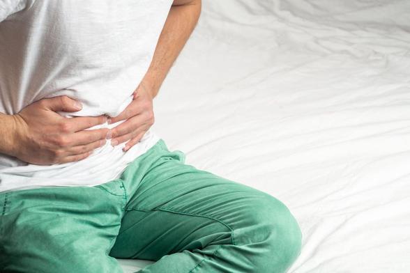 Man clutching abdomen. Image credit: Zvan Ivan via Shutterstock.
