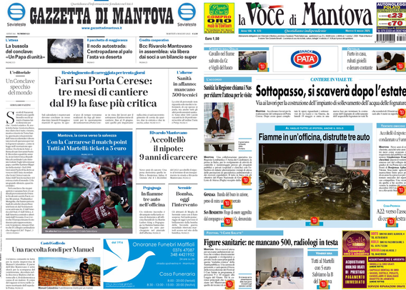 Un tablet mostra la prima pagina di due giornali affiancati. A sinistra c'è "Gazzetta di Mantova" e a destra "La Voce di Mantova". Entrambi i giornali hanno vari articoli con titoli e immagini. Alcuni titoli visibili includono "Fari su Porta Cerese: tre mesi di cantiere dal 19 la fase più critica" e "Sottopasso, si scaverà dopo l'estate". Ci sono immagini di persone e un'auto danneggiata. Sotto ci sono annunci pubblicitari e ulteriori articoli.  .