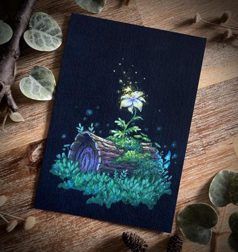 A photo of a portrait-format painting on black paper, placed on a wooden table and surrounded by branches and leaves for decoration. The painting features a lily-like white flower with a star-shaped stigma emitting glowing pollen, growing on a fallen, mossy tree trunk. The trunk is surrounded by grass, a few small ferns, and a couple glowing blue mushrooms.