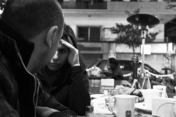 truly listen: black and white photograph of two people at a restaurant looking intensely at each other