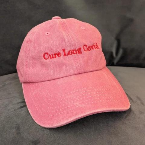 Pink cotton cap with tiny button on top. Red sown text: cure long covid