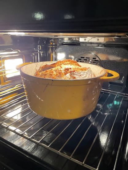 a freshly baked loaf of sourdough bread, in a heavy pot, still in the oven.