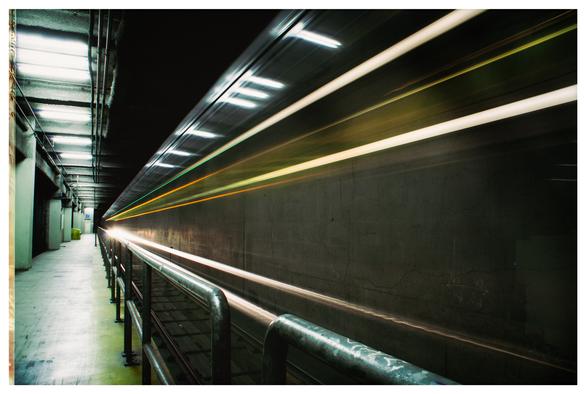 An 18 second exposure of a MUNI streetcar as it rushes through an underground station in downtown San Francisco. There's not much of the streetcar showing... just some orange and green and white streaks of light as the train rushes past the railings along the edge of the track. Mostly, you see bare concrete walls on the far right wall... And a brutally cold, glaring concrete passenger platform on the left.

There are no people in this picture. Everyone has moved to Canada.