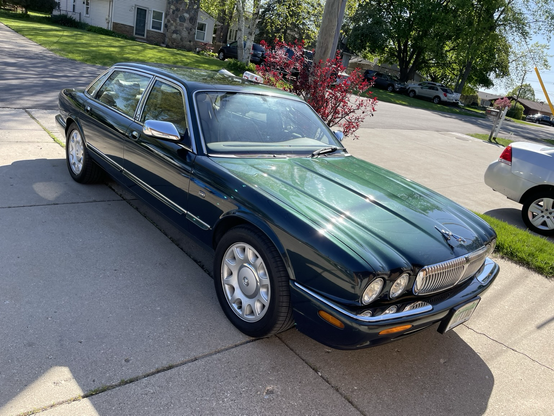 Photo of a green 1999 four-door Jaguar saloon sparkling in the springtime sunshine.
