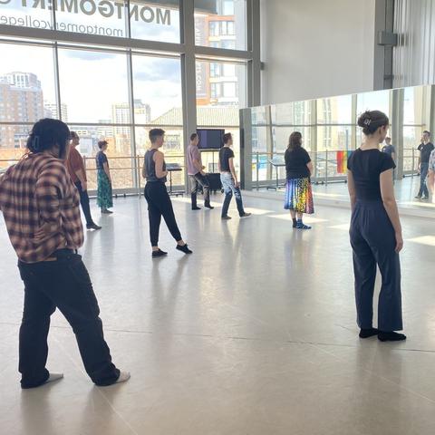 A teacher in the center of a circle of students demonstrates forward extension and some students try it out too.