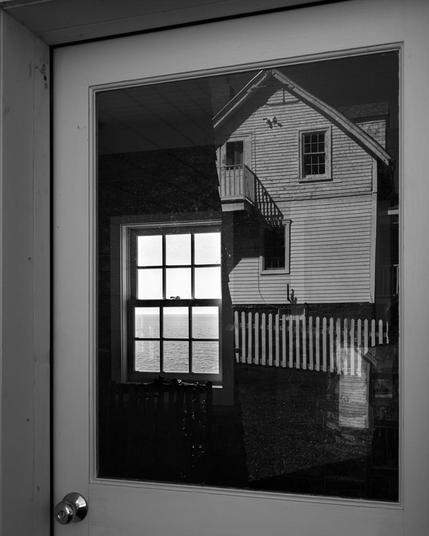 Reflections and windows showing many B&W mages all within one window frame.