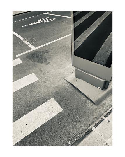 A glass information kiosk reflecting a cross walk