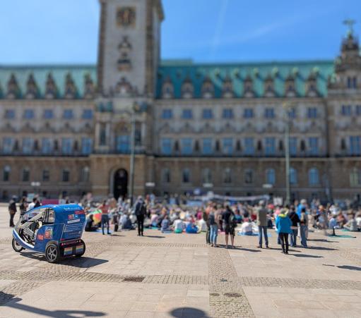 Rathausmarkt Hamburg. Im Hintergrund das Hamburger Rathaus. Auf dem Platz davor sitzen und stehen Demonstrierende.