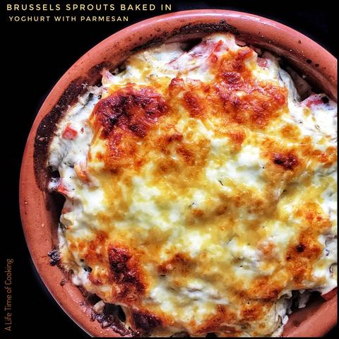 Brussels sprouts have been covered in a yoghurt sauce and baked in a clay pot. The top shows browning and some crispiness.